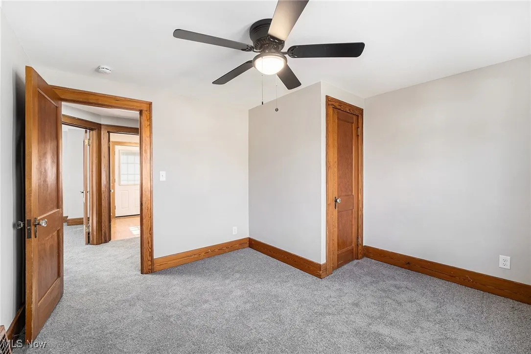 Carpeted spare room featuring a smoke detector and ceiling fan