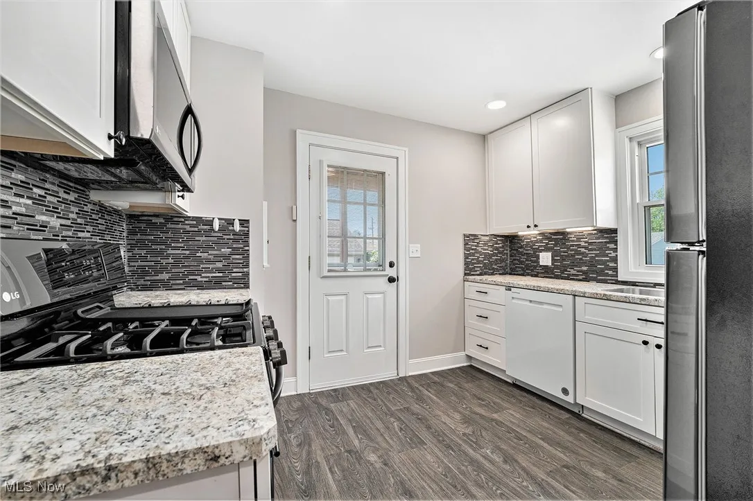 Kitchen featuring appliances with stainless steel finishes, healthy amount of natural light, dark wood finished floors, white cabinets, and recessed lighting