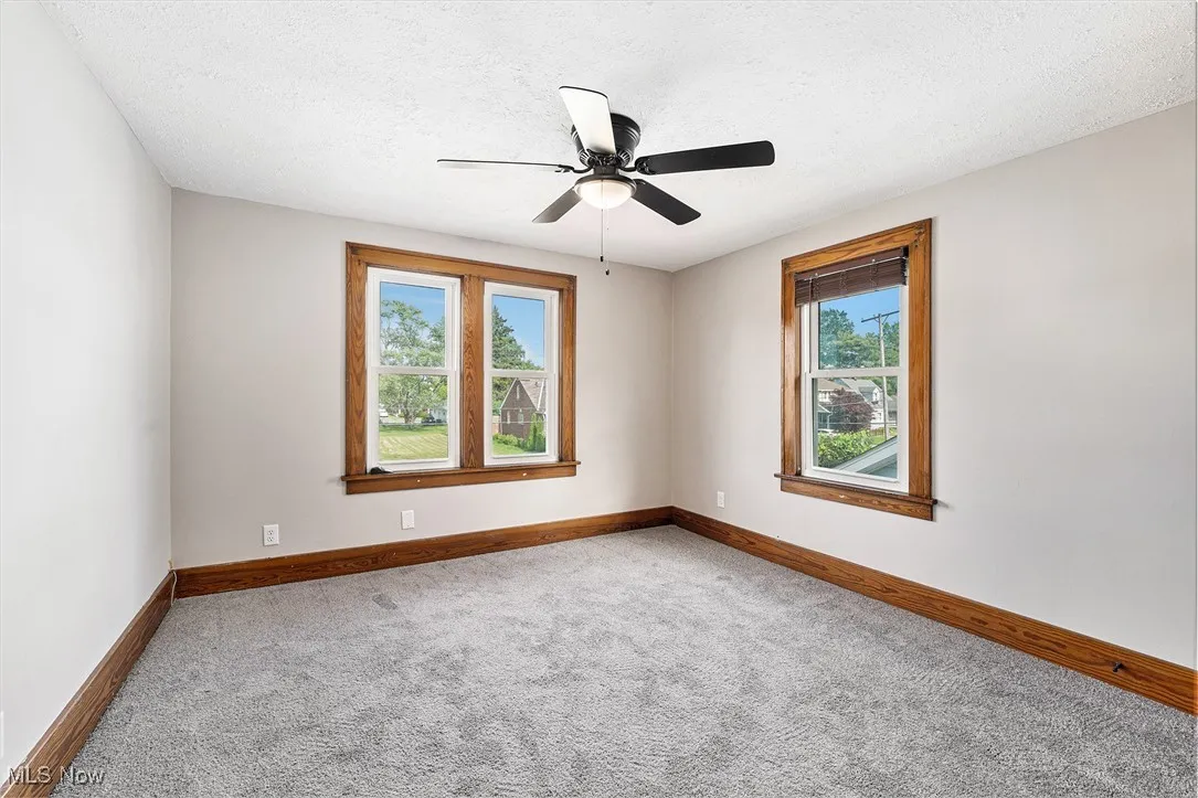 Unfurnished room featuring carpet, a ceiling fan, and a textured ceiling