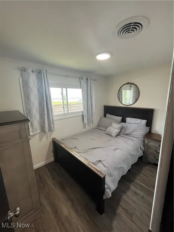 Bedroom with dark wood finished floors and baseboards