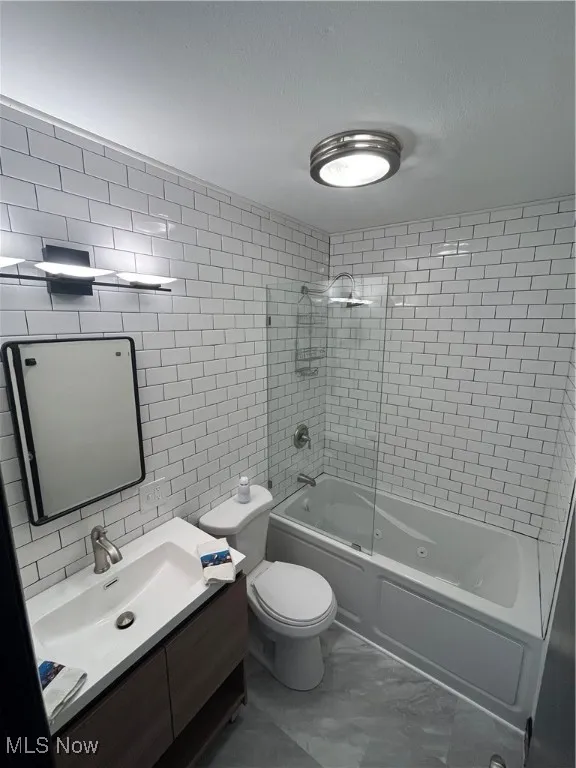 Full bathroom with tile walls, vanity, shower / washtub combination, marble finish floors, and a textured ceiling