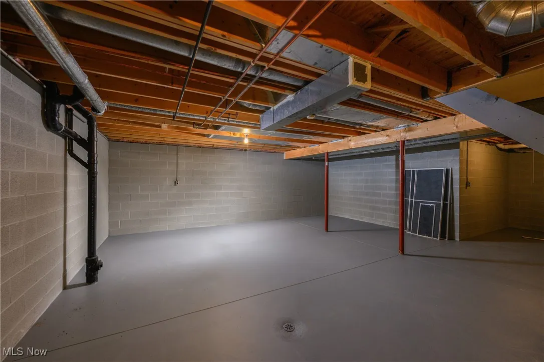 Unfinished basement featuring concrete block wall