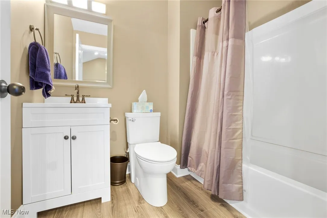 Bathroom featuring vanity, wood finished floors, and shower / tub combo with curtain