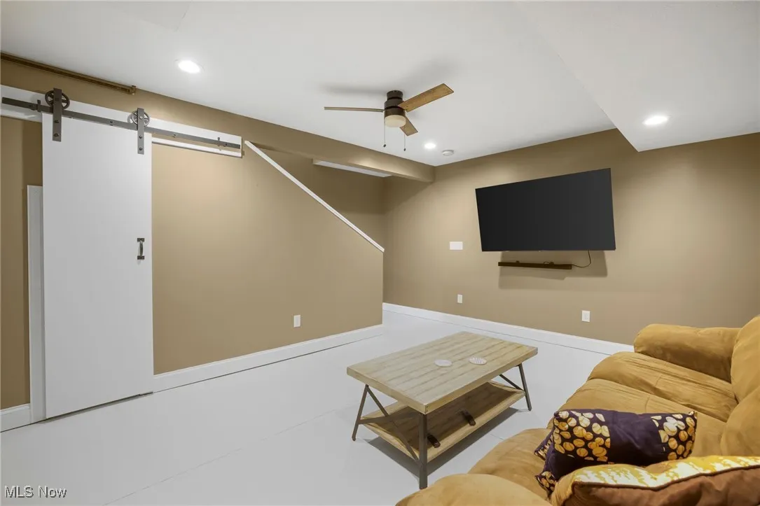 Living room with a barn door, ceiling fan, and recessed lighting