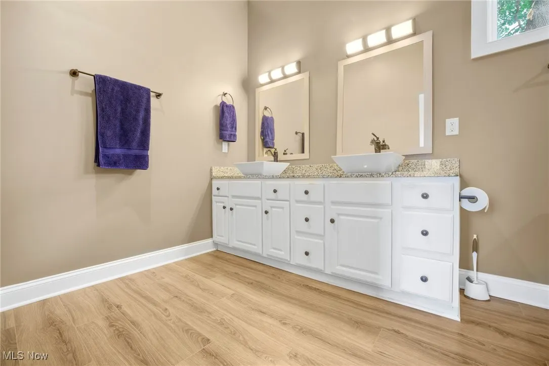 Full bathroom featuring double vanity and wood finished floors