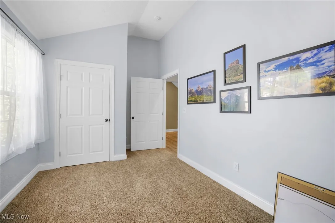 Unfurnished bedroom with carpet flooring and vaulted ceiling