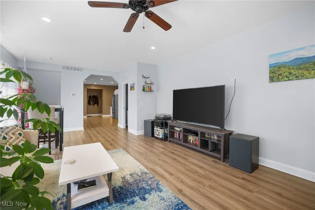 Living room featuring wood finished floors, a ceiling fan, arched walkways, and recessed lighting