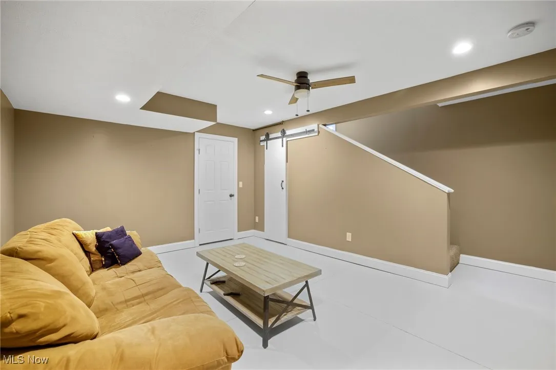 Living room featuring a barn door, a ceiling fan, and recessed lighting