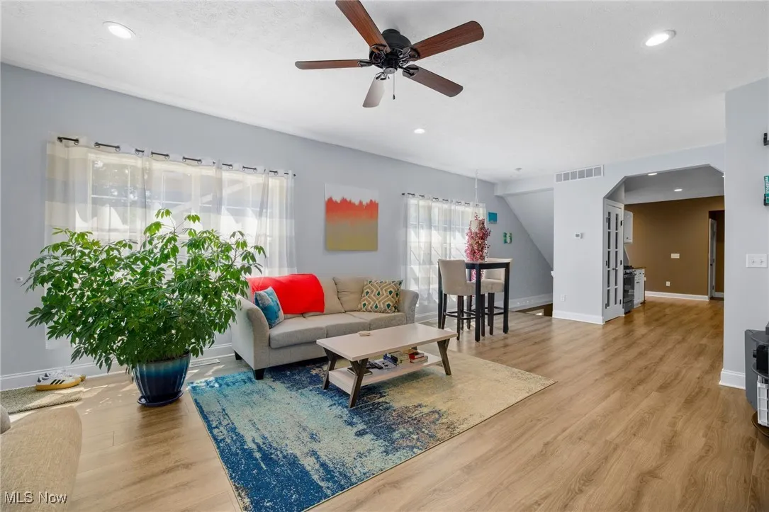 Living room featuring arched walkways, wood finished floors, recessed lighting, and ceiling fan