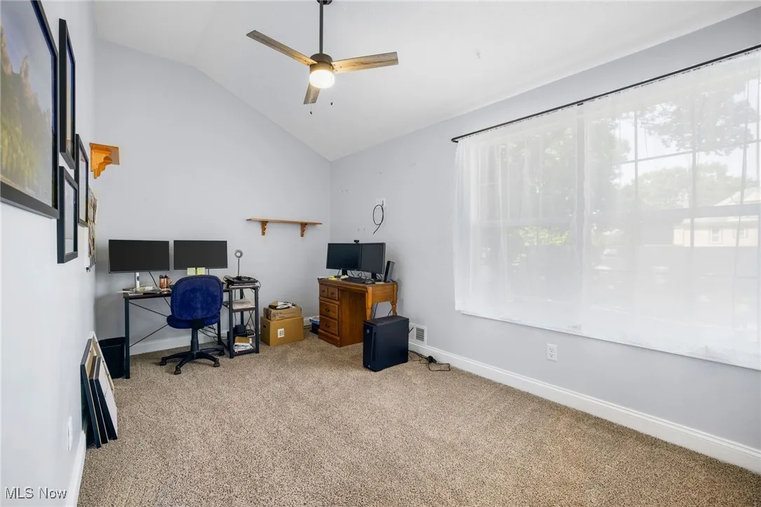 Office featuring a ceiling fan, carpet floors, lofted ceiling, and healthy amount of natural light