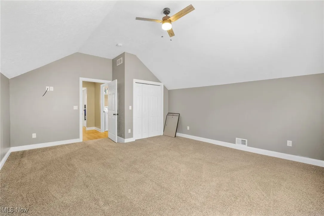 Additional living space with light carpet, lofted ceiling, and ceiling fan
