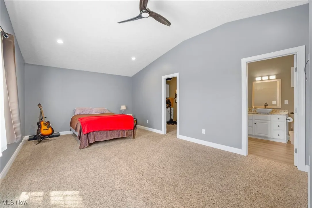 Bedroom featuring carpet floors, lofted ceiling, ensuite bath, a ceiling fan, and recessed lighting