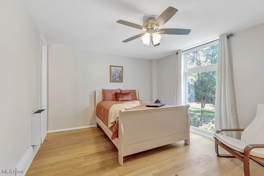 Bedroom featuring light wood-style flooring, ceiling fan, and radiator heating unit