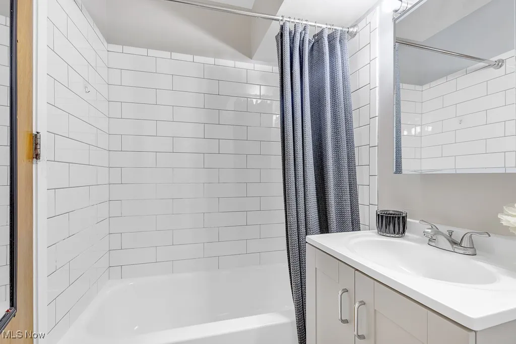 Full bath with shower / tub combo with curtain and vanity