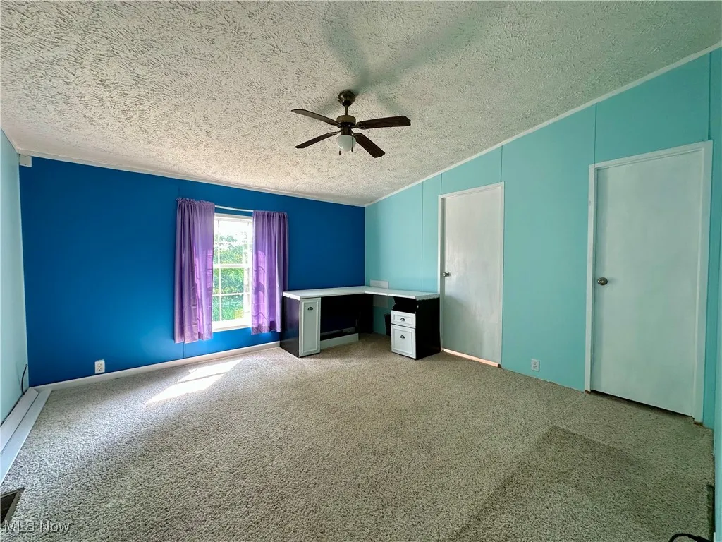 Unfurnished bedroom with a textured ceiling, carpet, vaulted ceiling, and a ceiling fan