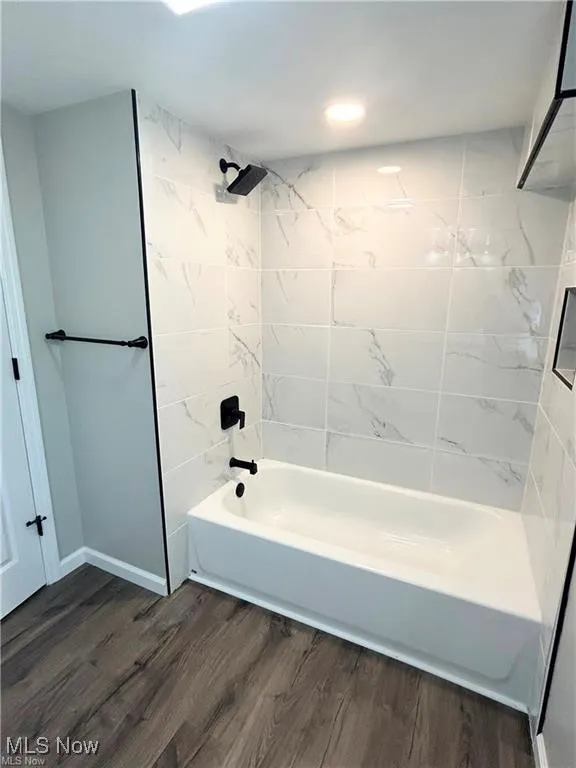 Full bath featuring wood finished floors and bathing tub / shower combination