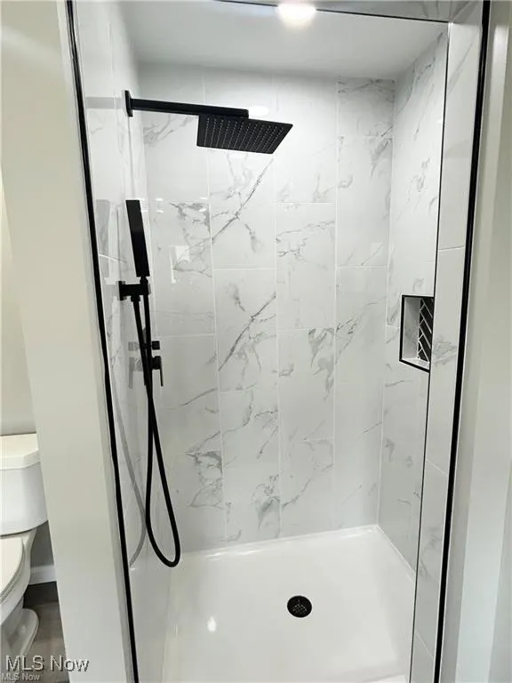 Bathroom with toilet and a marble finish shower