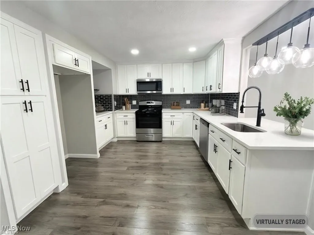 Kitchen featuring appliances with stainless steel finishes, backsplash, white cabinetry, recessed lighting, and dark wood-type flooring