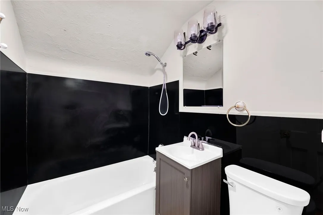 Bathroom with vanity, washtub / shower combination, and a textured ceiling