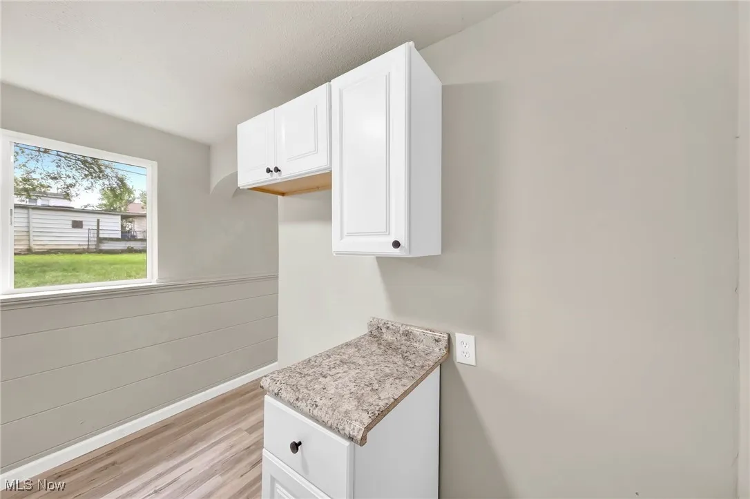 Kitchen with light wood finished floors, light countertops, and white cabinets