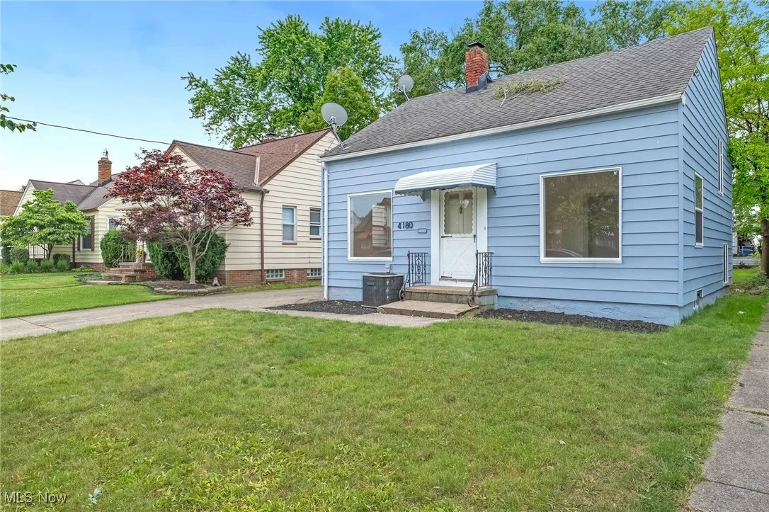 View of front of house featuring a front yard, a chimney, and a shingled roof
