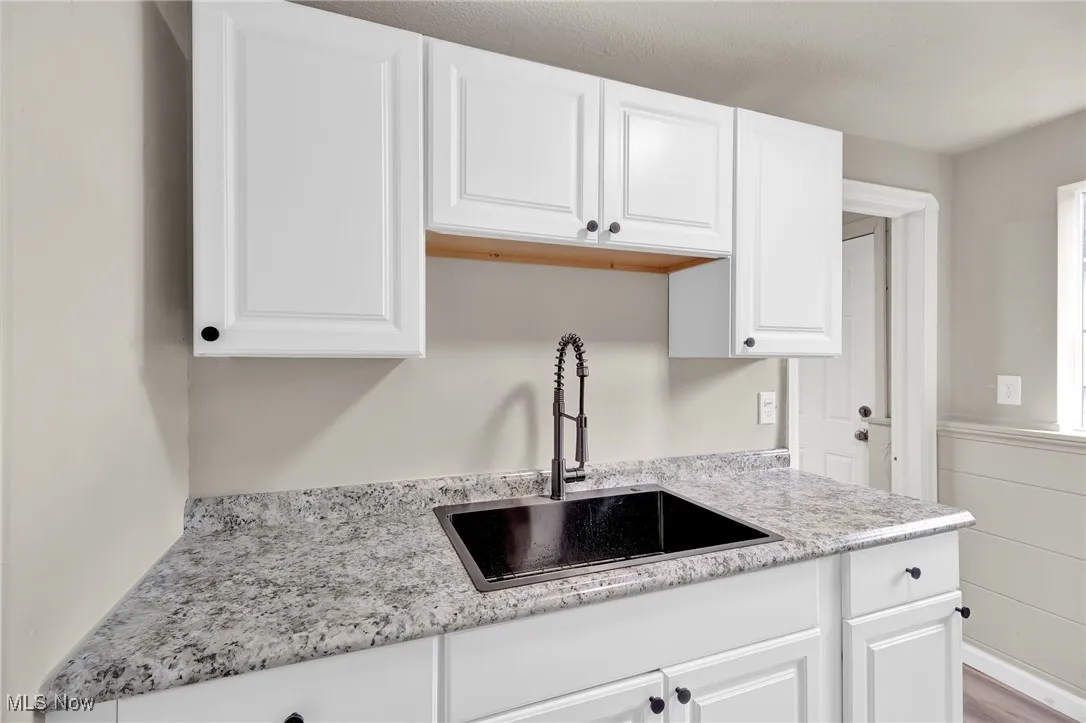 Kitchen featuring white cabinetry and light stone countertops