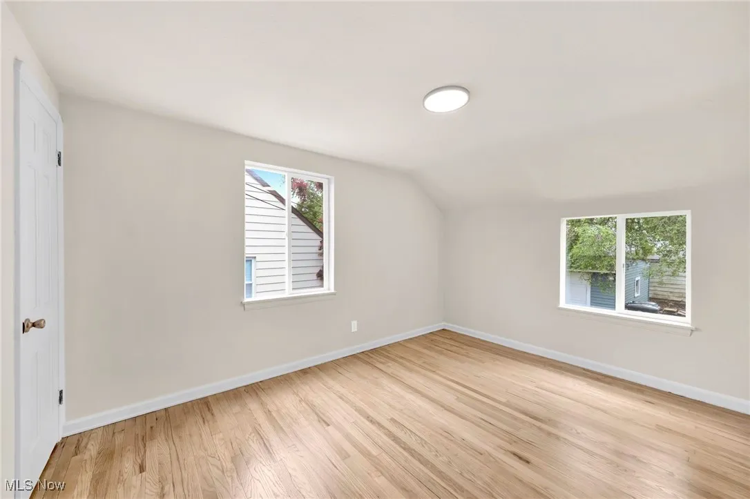Bonus room with light wood-type flooring and lofted ceiling