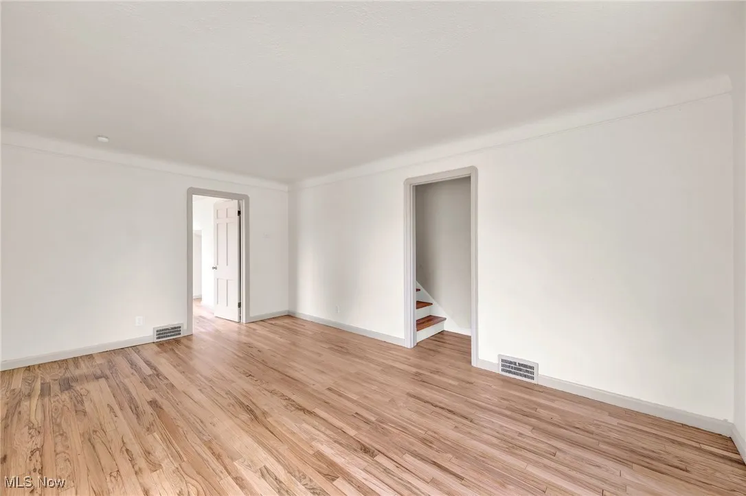 Unfurnished room featuring light wood finished floors and stairway