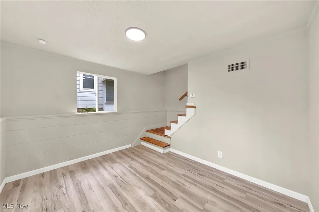 Below grade area featuring wood finished floors, stairs, and crown molding