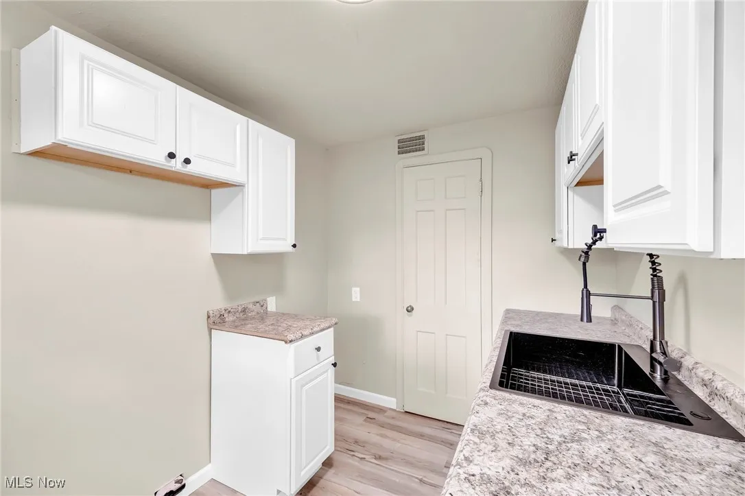 Kitchen with light wood-style floors, white cabinetry, and light countertops