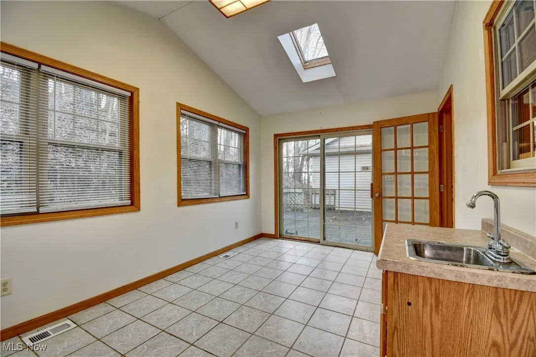 Dining area with a skylight, vaulted ceiling, and light tile patterned floors
