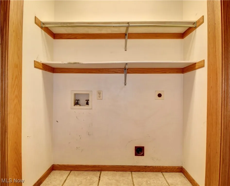 Washroom featuring hookup for an electric dryer, washer hookup, and light tile patterned floors