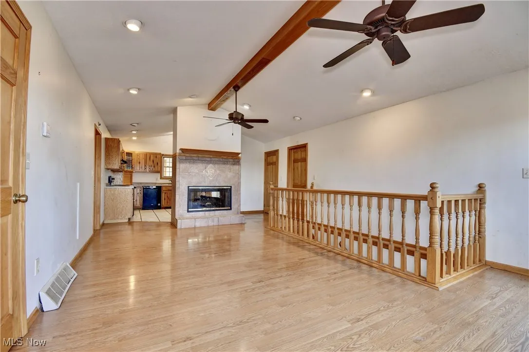 Unfurnished living room featuring a ceiling fan, light wood-style floors, and a tile fireplace