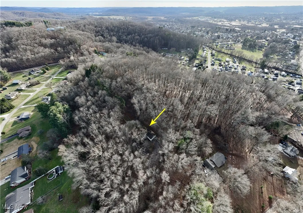Aerial view of property and surrounding area featuring a forest