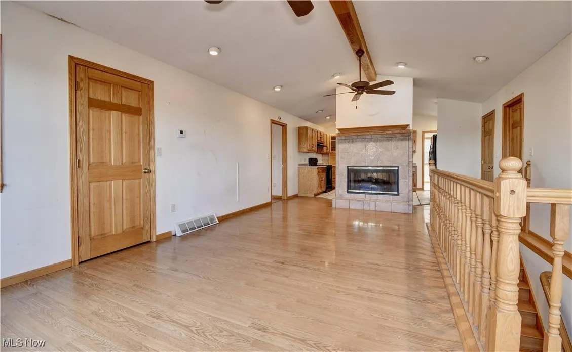 Unfurnished living room with ceiling fan, light wood-type flooring, a tile fireplace, and recessed lighting