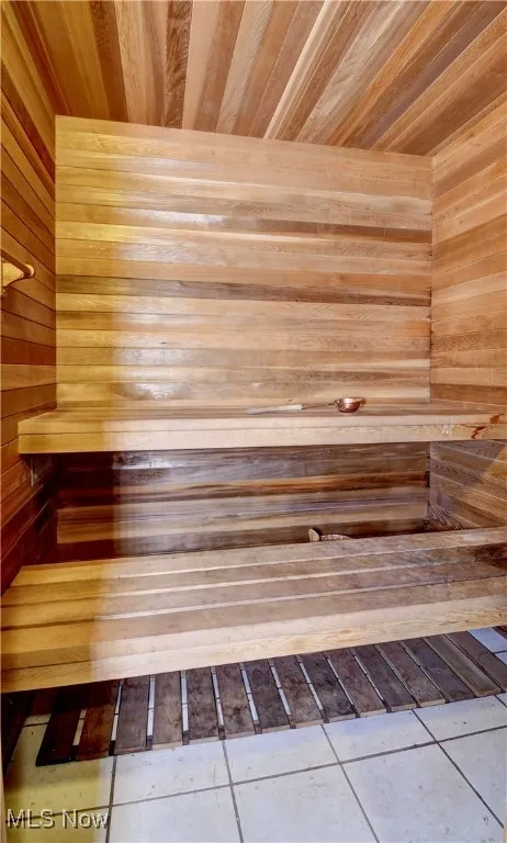 Sauna featuring tile patterned flooring, wood ceiling, and wooden walls