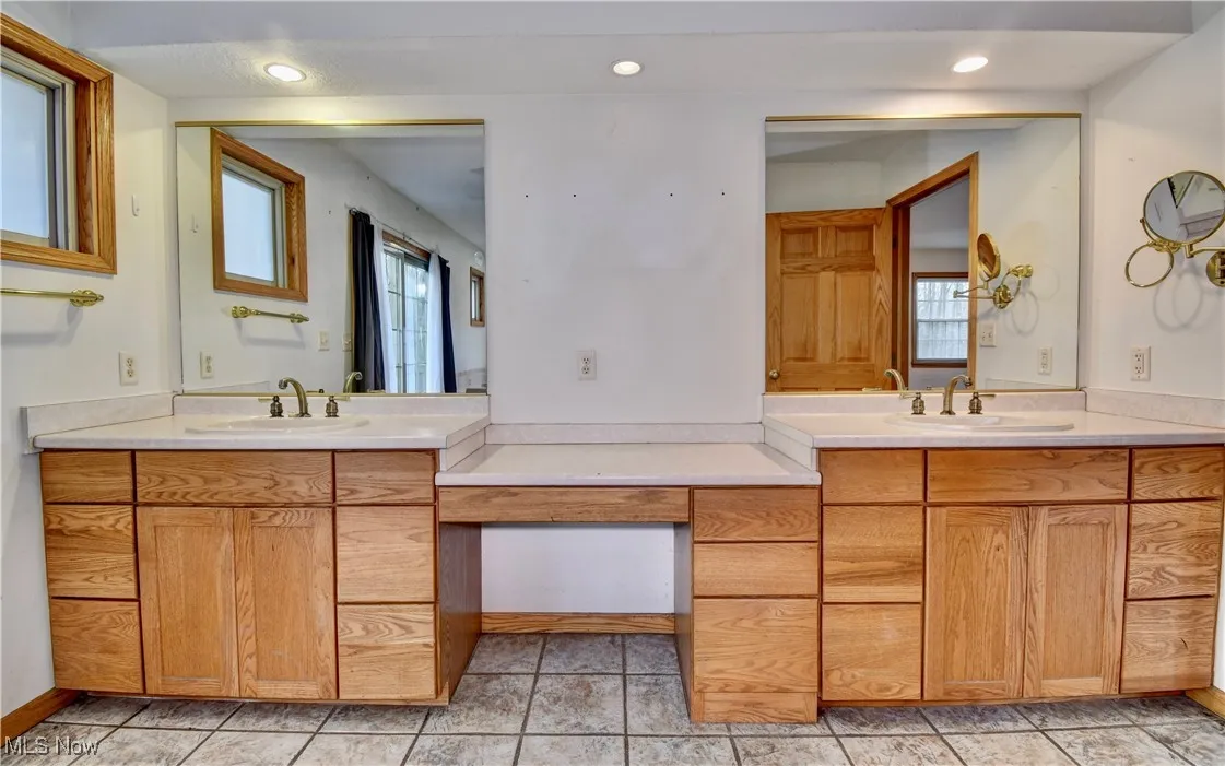 Bathroom featuring healthy amount of natural light, two vanities, and recessed lighting
