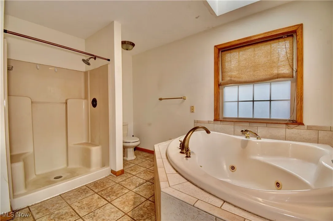 Full bath with a jetted tub, tile patterned flooring, and a shower
