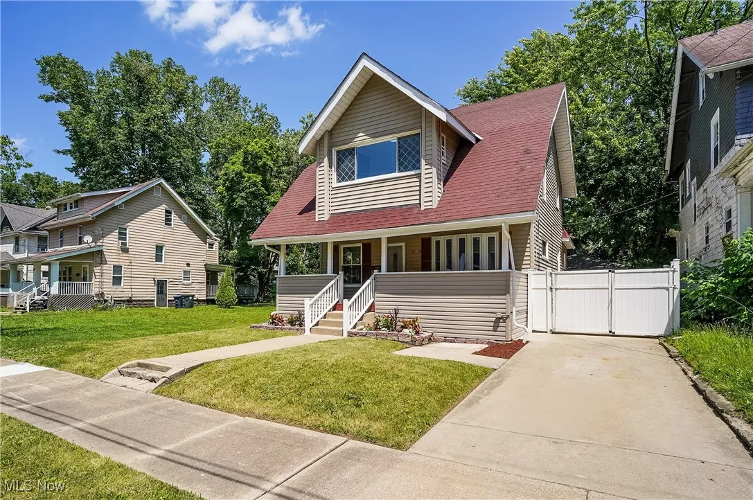 View of front of property featuring a gate, a porch, driveway, and a front lawn