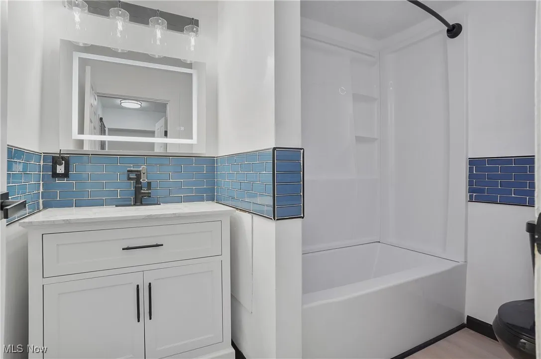 Full bathroom with  shower combination, vanity, and decorative backsplash