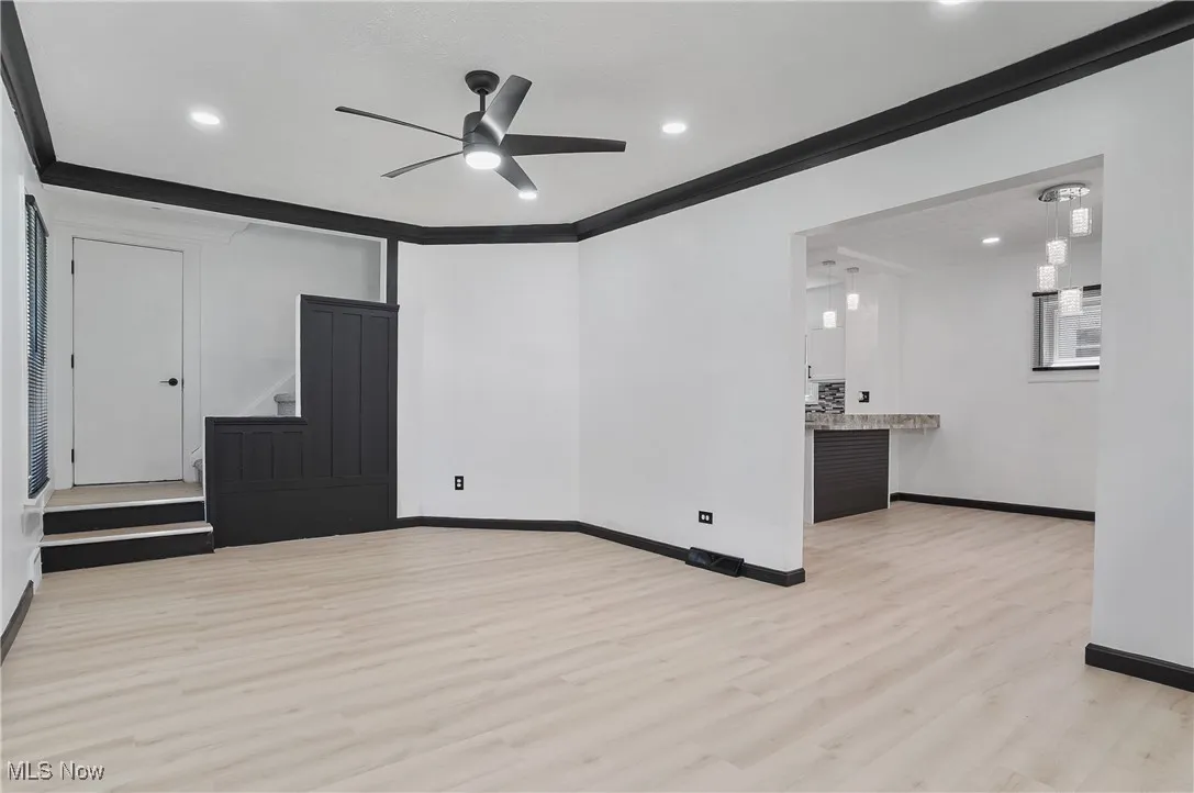 Empty room featuring wood finished floors, stairway, ceiling fan, crown molding, and recessed lighting
