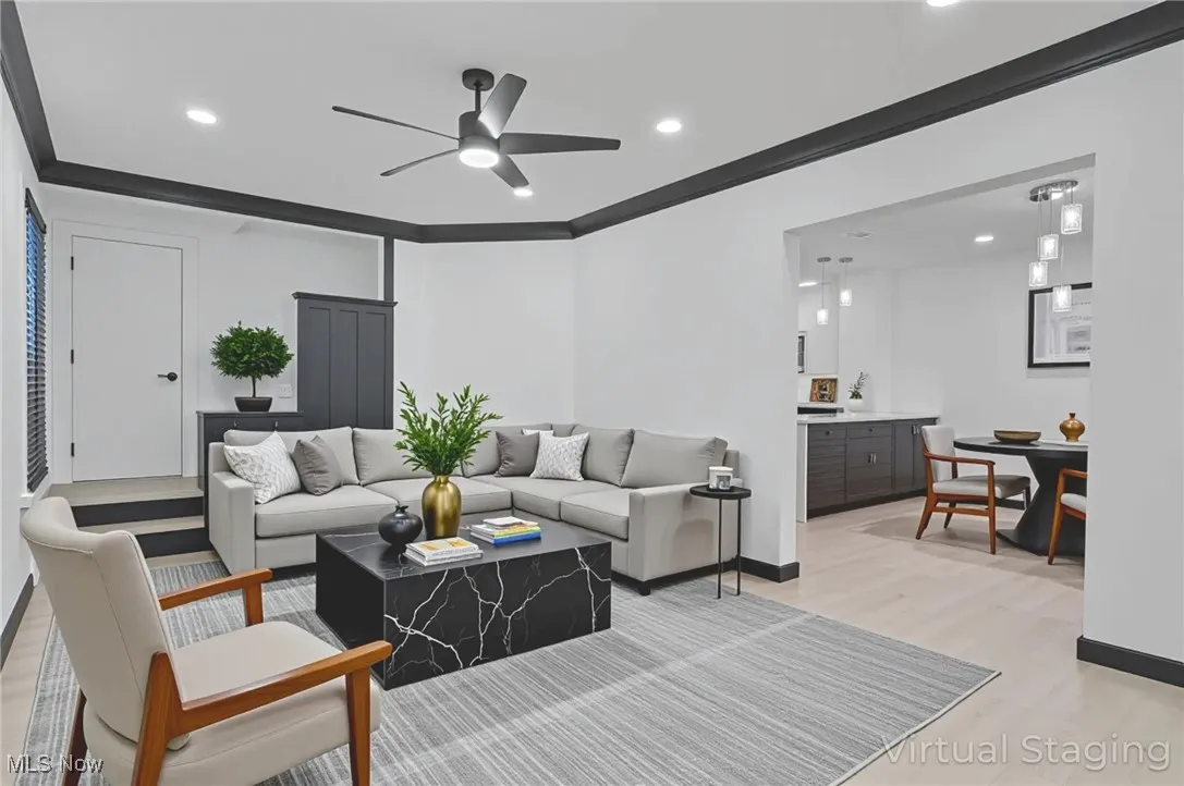 Living area featuring light wood-type flooring, a ceiling fan, recessed lighting, and ornamental molding