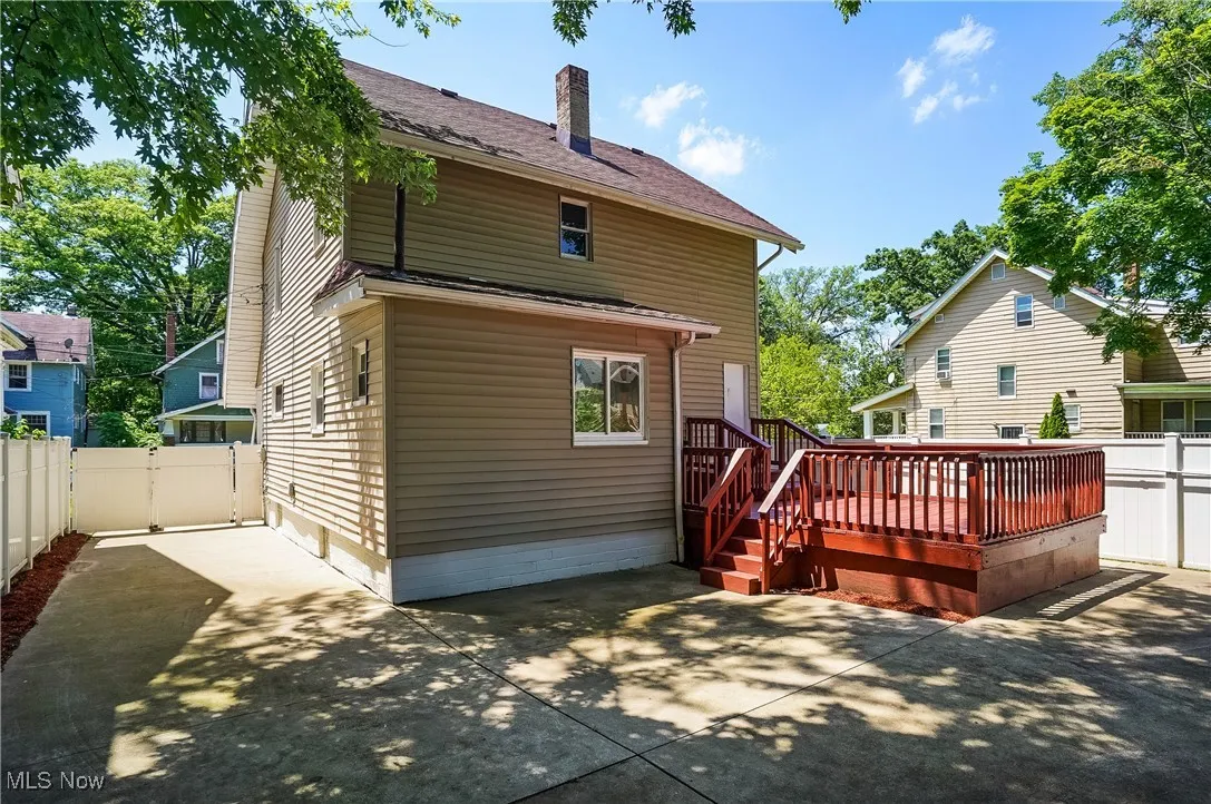 Rear view of house featuring a patio, a deck, a fenced backyard, a chimney, and a gate