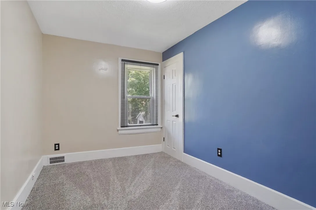 Carpeted spare room featuring baseboards