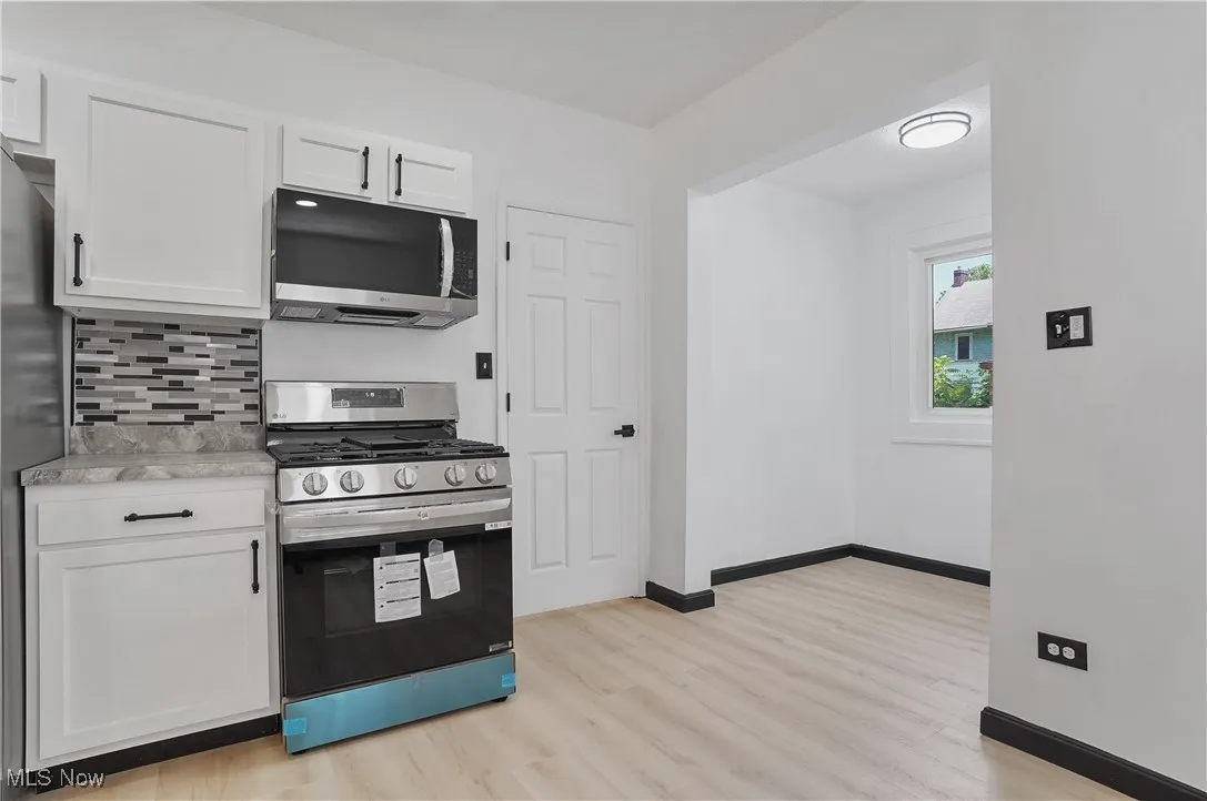 Kitchen featuring appliances with stainless steel finishes, white cabinetry, light wood-type flooring, and light countertops