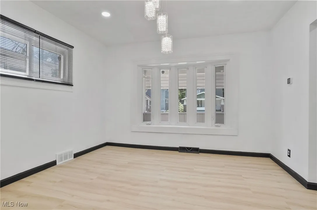 Unfurnished room with wood finished floors, recessed lighting, and a chandelier