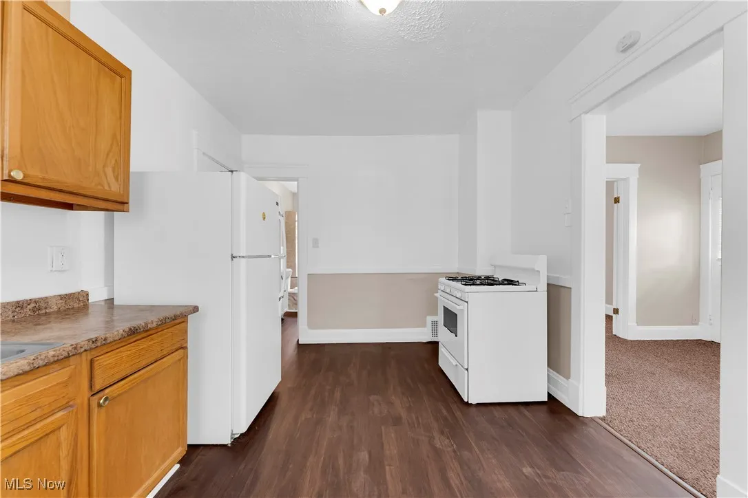 Kitchen with white appliances and dark wood-style floors