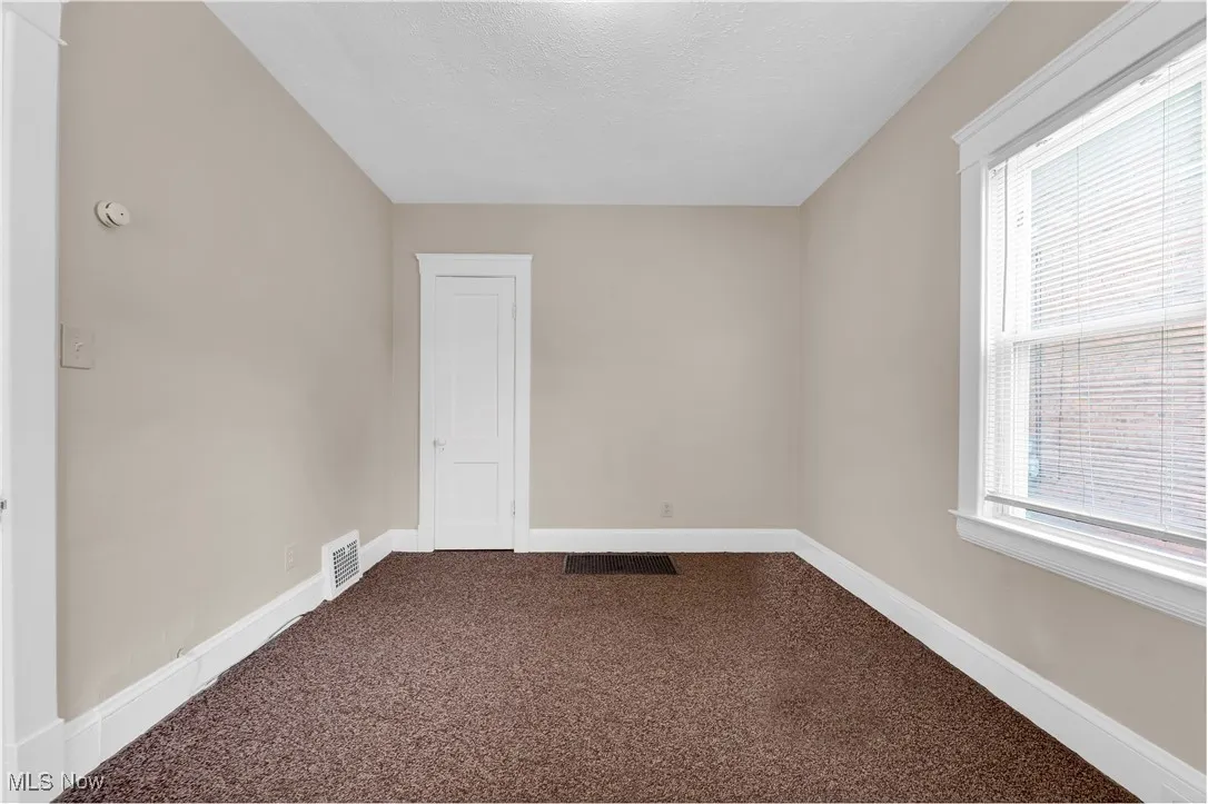 Unfurnished room with dark carpet and a textured ceiling