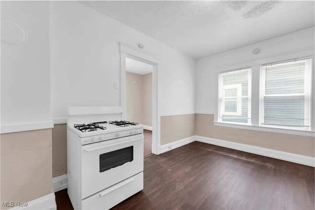 Kitchen featuring white gas range, dark wood-style flooring, and a textured ceiling