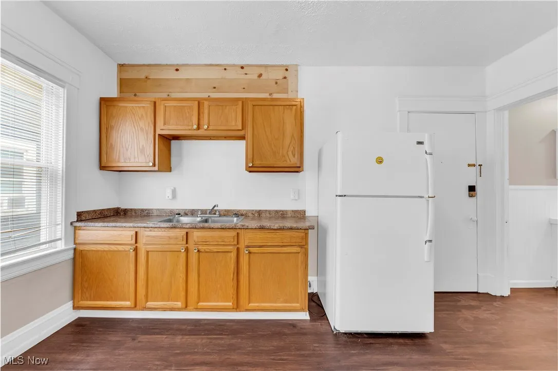 Kitchen with freestanding refrigerator, dark wood finished floors, and dark countertops